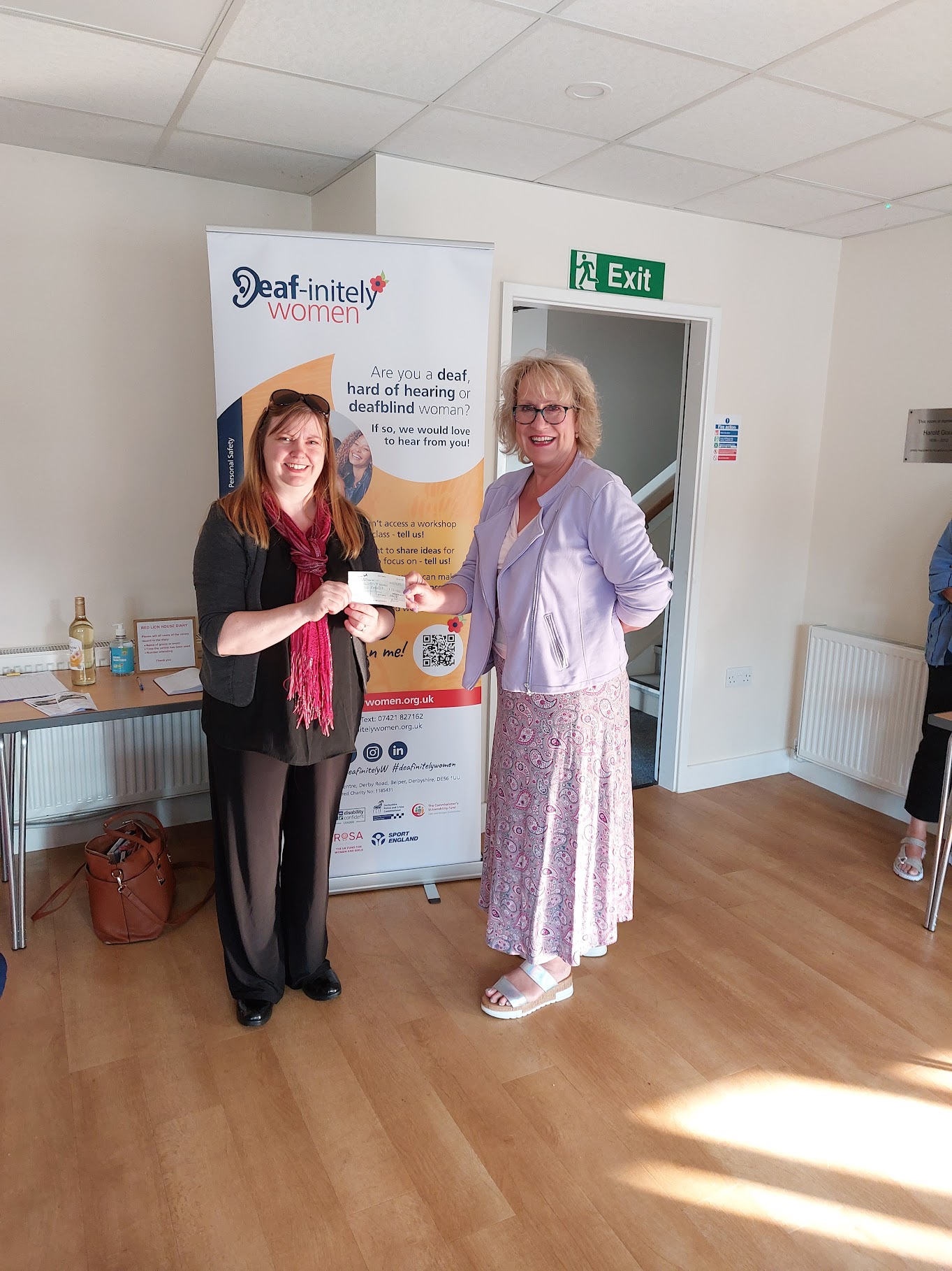 Two women together holding a cheque of donation.